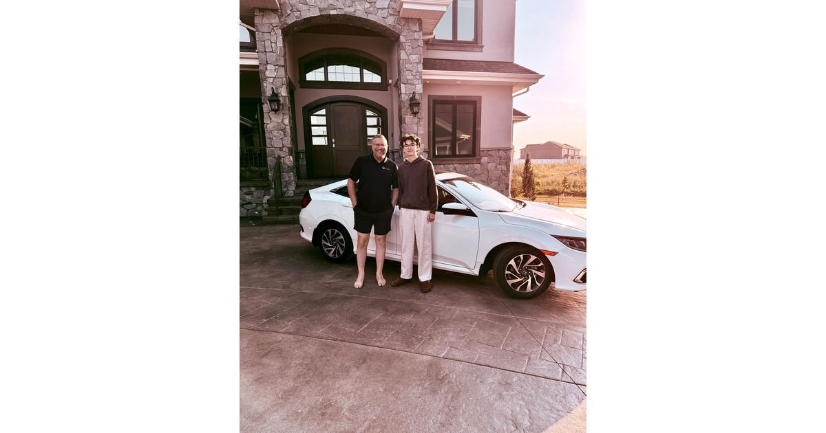 Jayson Lowe and his nephew Evan stand in a driveway beside the white car financed through a family bank policy loan